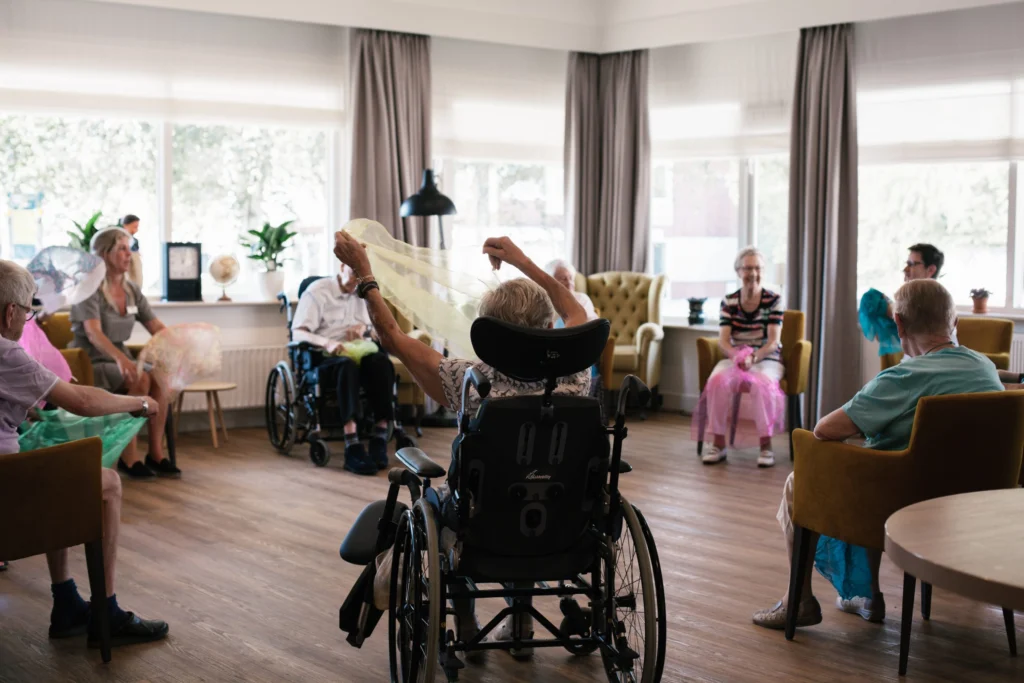 Gezellig ingerichte woonkamer met comfortabele stoelen, grote ramen en groene planten in Maanderzand woonzorgcentrum